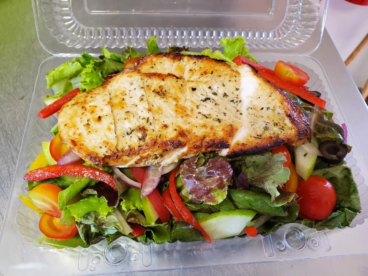 Grilled chicken salad with mixed greens, peppers, olives and cherry tomatoes, made fresh to order